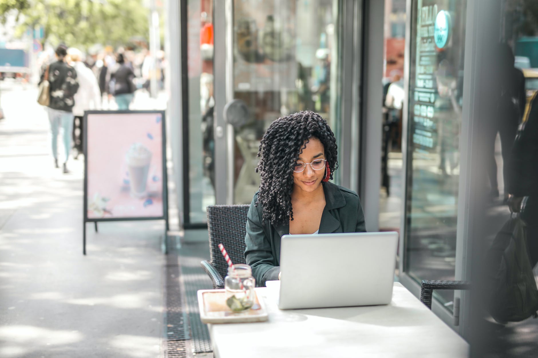 growing a business online using seo. a lady sitting outside on her laptop next to a shop.