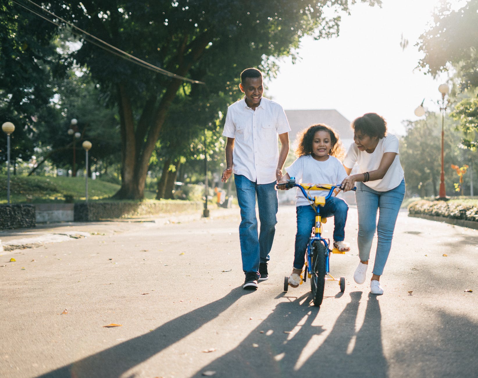family helping young girl ride a bike