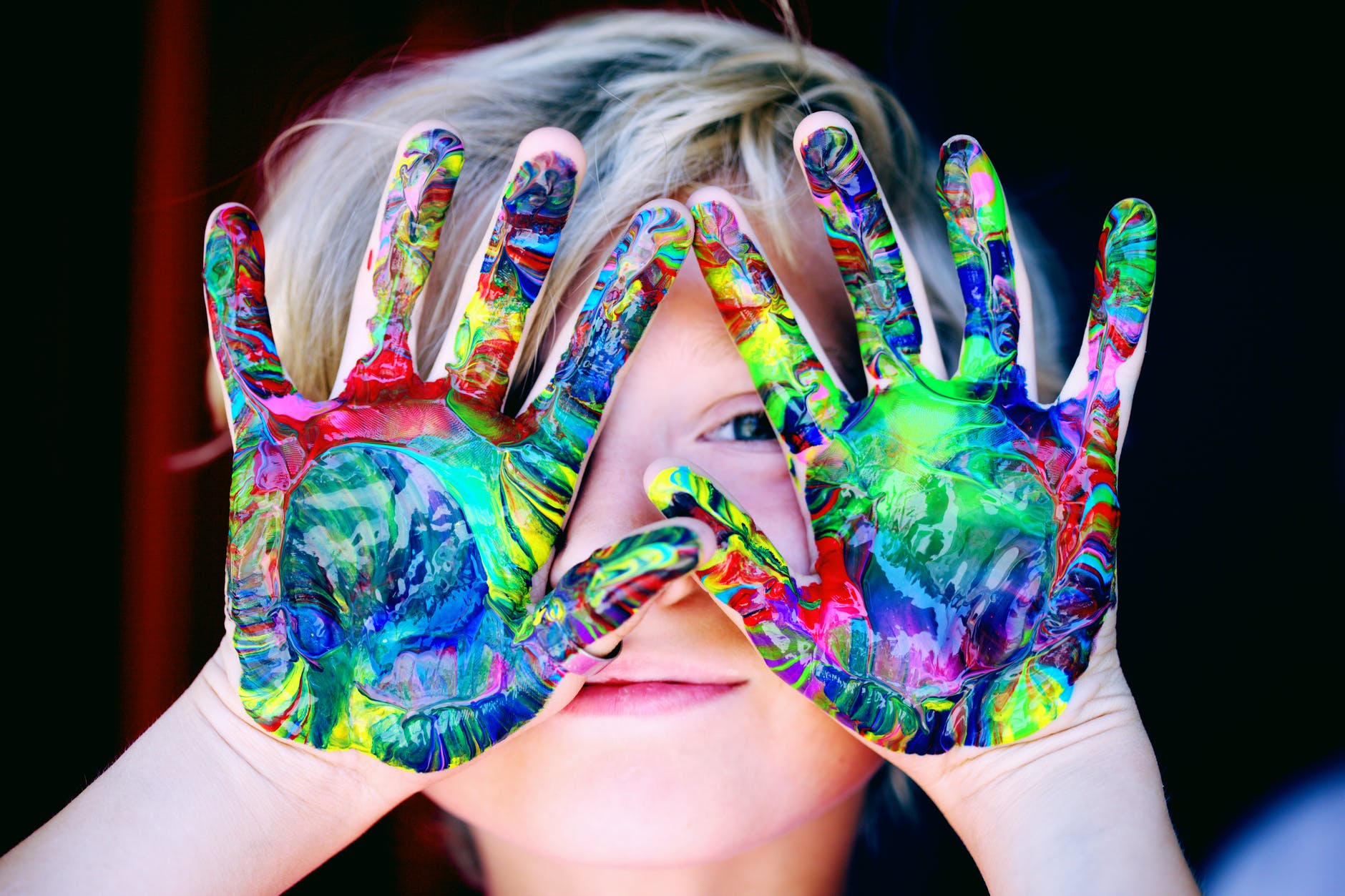 Child with colorful paint on his hands for choosing logo colors in brand building